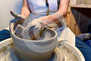 close up of ceramist woman hands working and shaping clay on the lathe or potter's wheel inside a pottery workshop