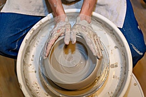 close up of ceramist woman hands working and shaping clay on the lathe or potter's wheel inside a pottery workshop