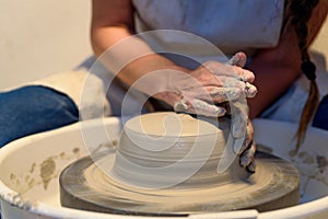 close up of ceramist woman hands working and shaping clay on the lathe or potter's wheel inside a pottery workshop