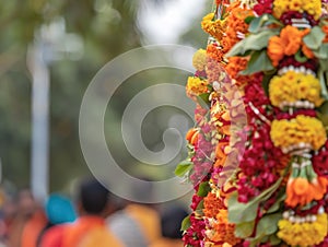 Close-up of a ceremonial procession with a pole decorated with a bunch of colorful flowers held by devotees