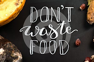Close up of a chalkboard with Don`t waste food lettering and rotten fruits. Selective focus