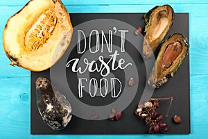 Close up of a chalkboard with Don`t waste food lettering and rotten fruits. Selective focus