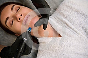 Close-up of a charming middle aged woman getting facial hydro microdermabrasion peeling treatment at cosmetic beauty spa clinic.