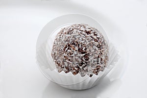 Close up on a chocolate and coconut rum ball on a white plate