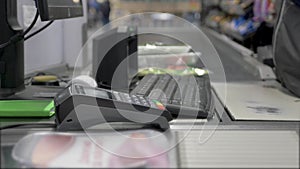 Close up check out counter. Senior female hands in medical gloves working on cash register in the supermarket due to COVID-19.