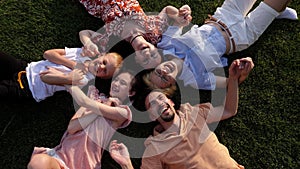 Close-up of a cheerful big family lying down together on the grass in a circle.