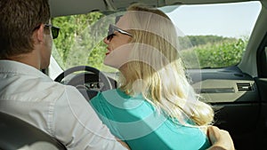 CLOSE UP: Cheerful blonde girl looks at boyfriend driving them through country.