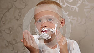 Close-up of a cheerful boy applying shaving foam at home in the bathroom.