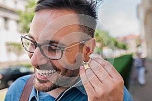 Close-up of cheerful businessman wearing headphones while standing on sidewalk