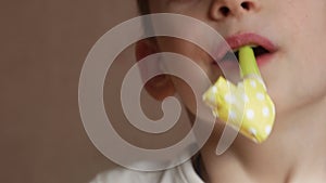 Close-up of a cheerful Caucasian preschooler boy blowing a paper festive pipe. Child`s birthday. Happy child with a festive tune.