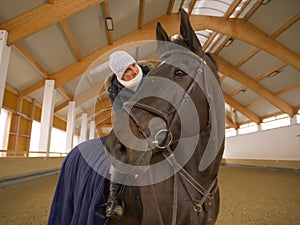 CLOSE UP Cheerful Caucasian woman sitting and stroking the beautiful brown horse