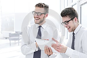 Close up.cheerful employees looking at the digital tablet screen