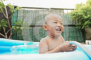 close up cheerful little boy playing water hose in the outdoor pool