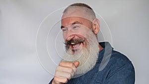 Close up of cheerful mature man with gray beard. Senior man laughing hysterically on grey background
