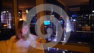 CLOSE UP: Cheerful woman sitting on the couch and texting from hotel room in NYC