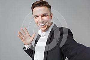 Close up of cheerful young business man in black suit shirt isolated on grey background. Achievement career wealth