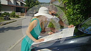 CLOSE UP: Cheerful young couple planning their summer road trip vacation on map