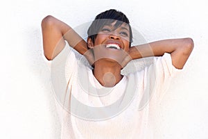 Close up cheerful young lady with hands behind head on white background