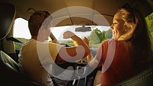 CLOSE UP: Cheerful young man and woman dance during road trip on sunny evening.