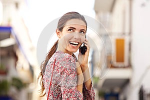 Close up cheerful young woman talking on mobile phone and laughing outside