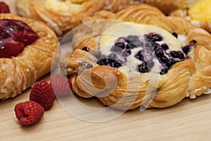 Close up of cheese danishes puff pastry with cherry jam, blackberries and fresh raspberries