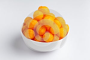 Close up of Cheese Potato Puff Ball Snacks, tangy orange color, Popular Ready to eat crunchy and puffed snacks,  salty in white