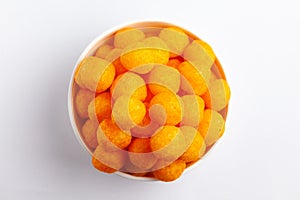 Close up of Cheese Potato Puff Ball Snacks, tangy orange color, Popular Ready to eat crunchy and puffed snacks,  salty in white