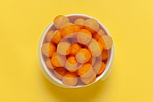 Close up of Cheese Potato Puff Ball Snacks, tangy orange color, Popular Ready to eat crunchy and puffed snacks,  salty in white