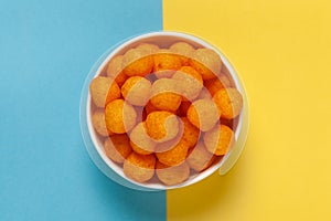 Close up of Cheese Potato Puff Ball Snacks, tangy orange color, Popular Ready to eat crunchy and puffed snacks,  salty in white