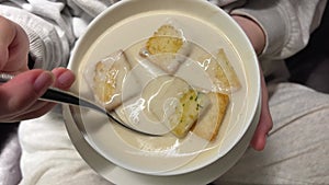 close-up cheese soup in a bowl with croutons, girl stirs soup with a spoon. slow motion