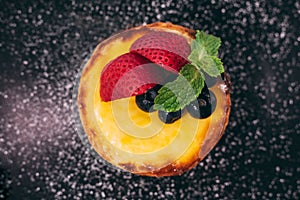 Close up Cheese tart topping with slices of strawberry and blackberry with icing sugar