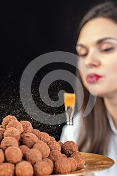 Close-up chef decorates pile of dark chocolate truffles with gold luster dust