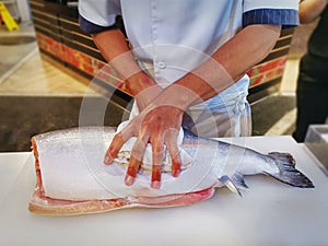 Chef Filleting Salmon on Table at Japanese Restaurant