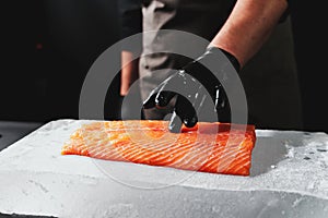 Close-up of chef hand prepared to cooking fresh salmon fille