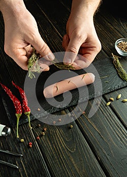 Close-up of a chef hands adding dry aromatic spices to sausage on the kitchen table. The concept of preparing a delicious