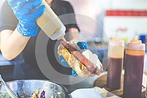 Man holding hot dog and adding mustard. Street fast food vendor concept