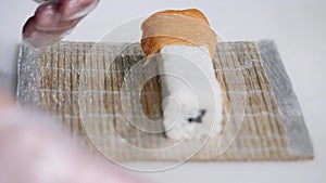 Close-up of chef hands preparing japanese food making sushi at restaurant. Young cook serving traditional modern japan