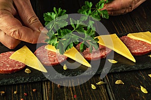 Close-up of a chef hands serving a cheese and sausage appetizer on a kitchen table before serving in a restaurant
