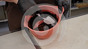 Close-up of the chef mixing the melted chocolate in a bowl with a spatula.