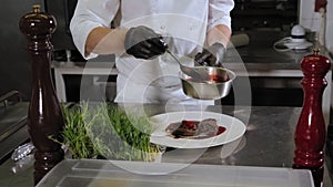 Close-up of the chef pouring a juicy beef steak sauce with strawberries.