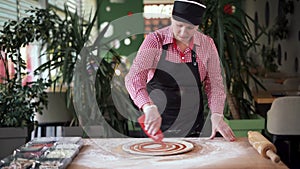 Close-up of a chef pouring tomato sauce over pizza dough. Traditional Italian pizza restaurant. Pizzeria baker preparing