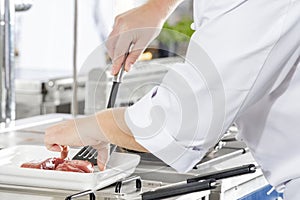 Close-up of a chef prepares beef steak in pan at the kitchen