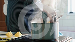 Close-up of chef puts a pasta in a steaming saucepan on a stove