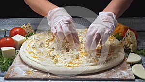 Close-up of chef`s hands adding a blue cheese in four cheeses pizza on a wooden board. Frame. Delicious pizza