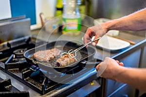 Close-up of chef`s hands while baking meat
