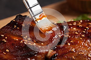 Close-up chef spreading sauce bbq on ribs with brush