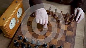 Close up chess game, male hand makes first move with wooden pawn, vintage wooden chess, selective focus