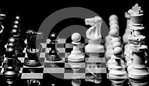 Close up of Chess pieces on a reflective mirror board surface wi