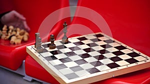 Close up of chess on stadium bleacher. Body part of unrecognizable woman playing in board game in cold weather.