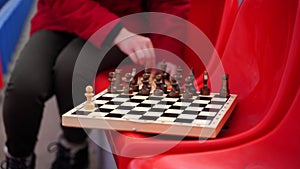 Close up of chess on stadium bleacher. Body part of unrecognizable woman playing in board game in cold weather.